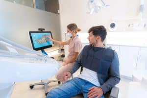 Dentist using modern technology to explain the dental procedure to a man sitting on the clinic