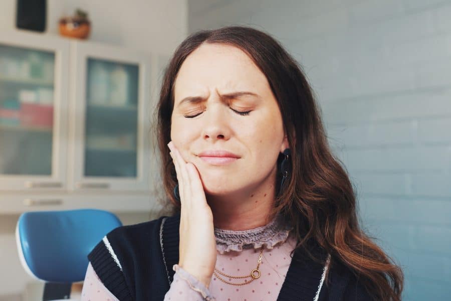 closeup of a woman with her hand on jaw, serious pain possible infection